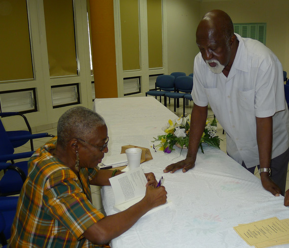 Dr. Velma Pollard signing copies of her book for Prof. Mervyn Morris